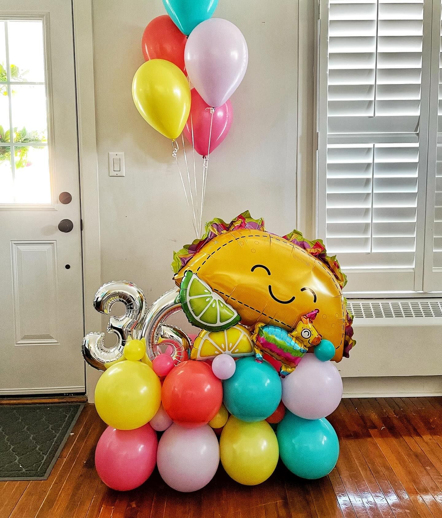 Balloon arrangement with a smiling taco, colorful balloons, and