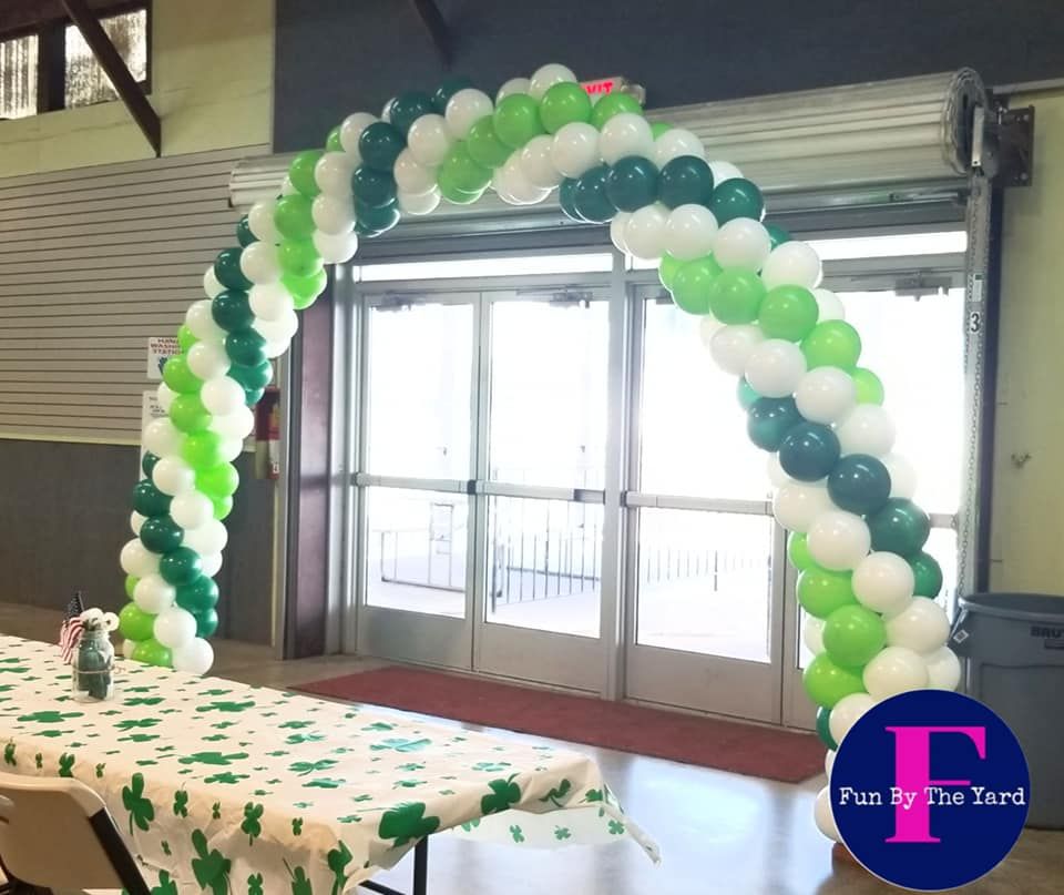 A green and white balloon arch in front of a door