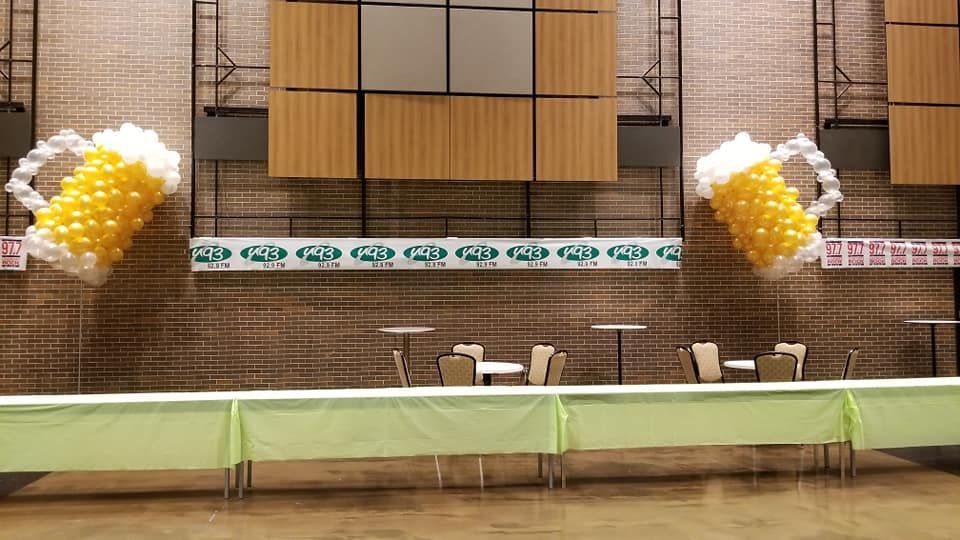 A room with tables and chairs and balloons in the shape of a beer mug.