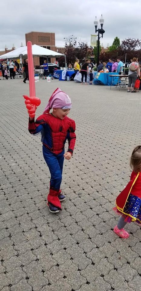 Happy boy in Spiderman costume holding a  balloon animal
