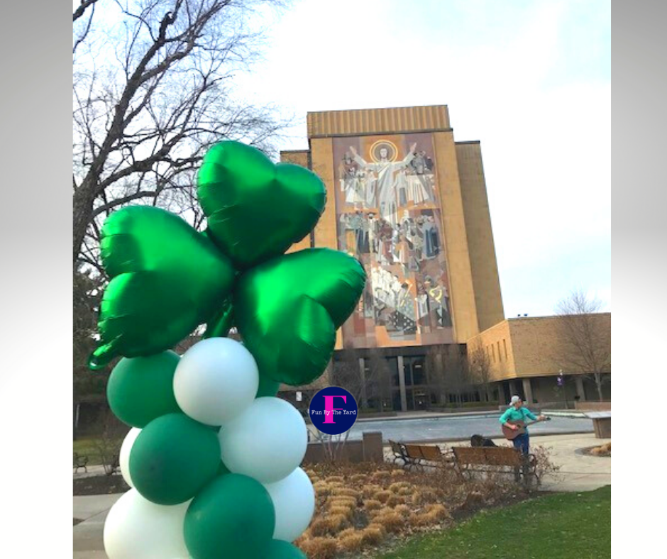 A bunch of green and white balloons in front of a building