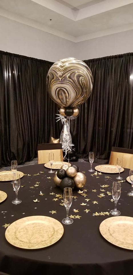 A table with plates , glasses , and balloons on it.