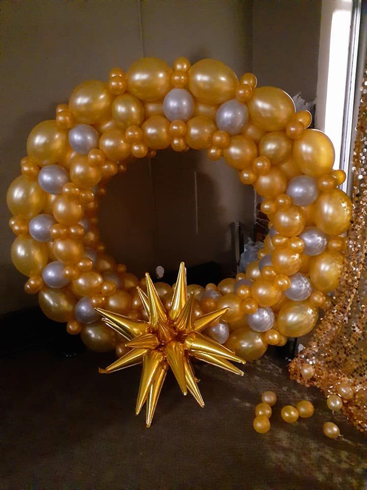 A wreath made of gold and silver balloons with a star in the middle.
