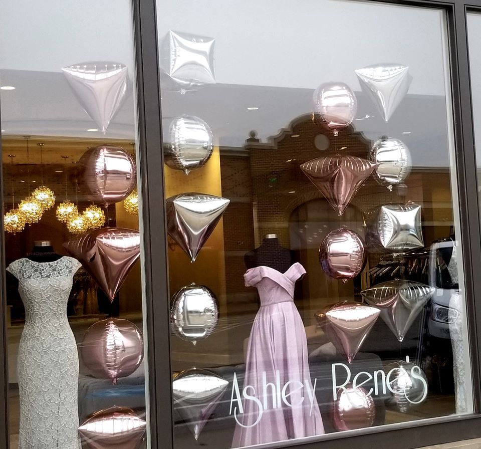 Window display with dresses and pink/silver balloons,