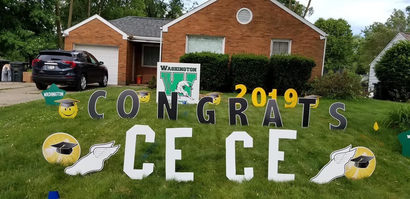 A brick house with a congratulations sign in front of it.