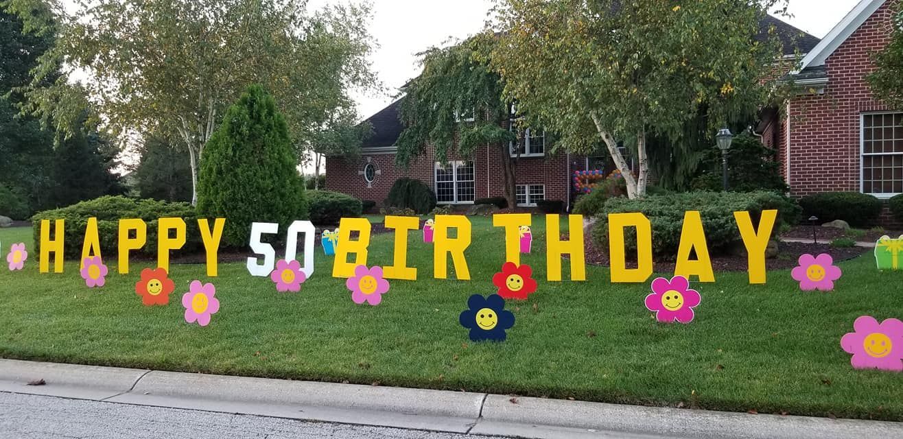 A happy 50th birthday sign is in the grass in front of a house.