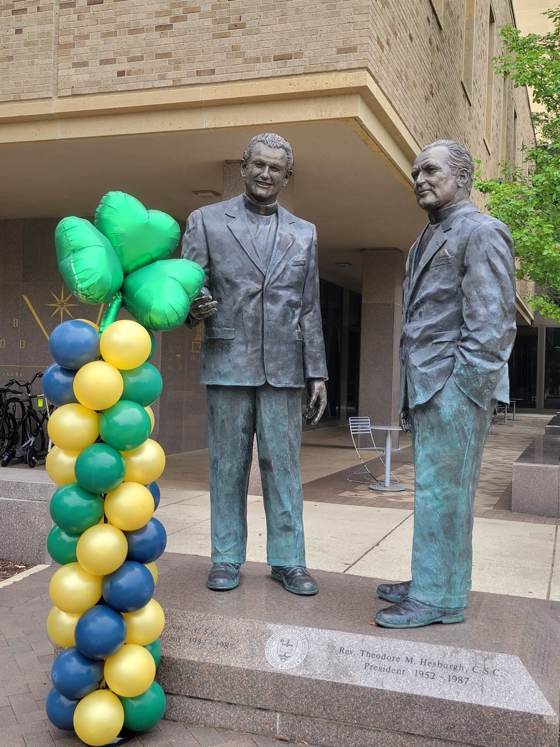 A statue of two men standing next to each other with balloons in front of them