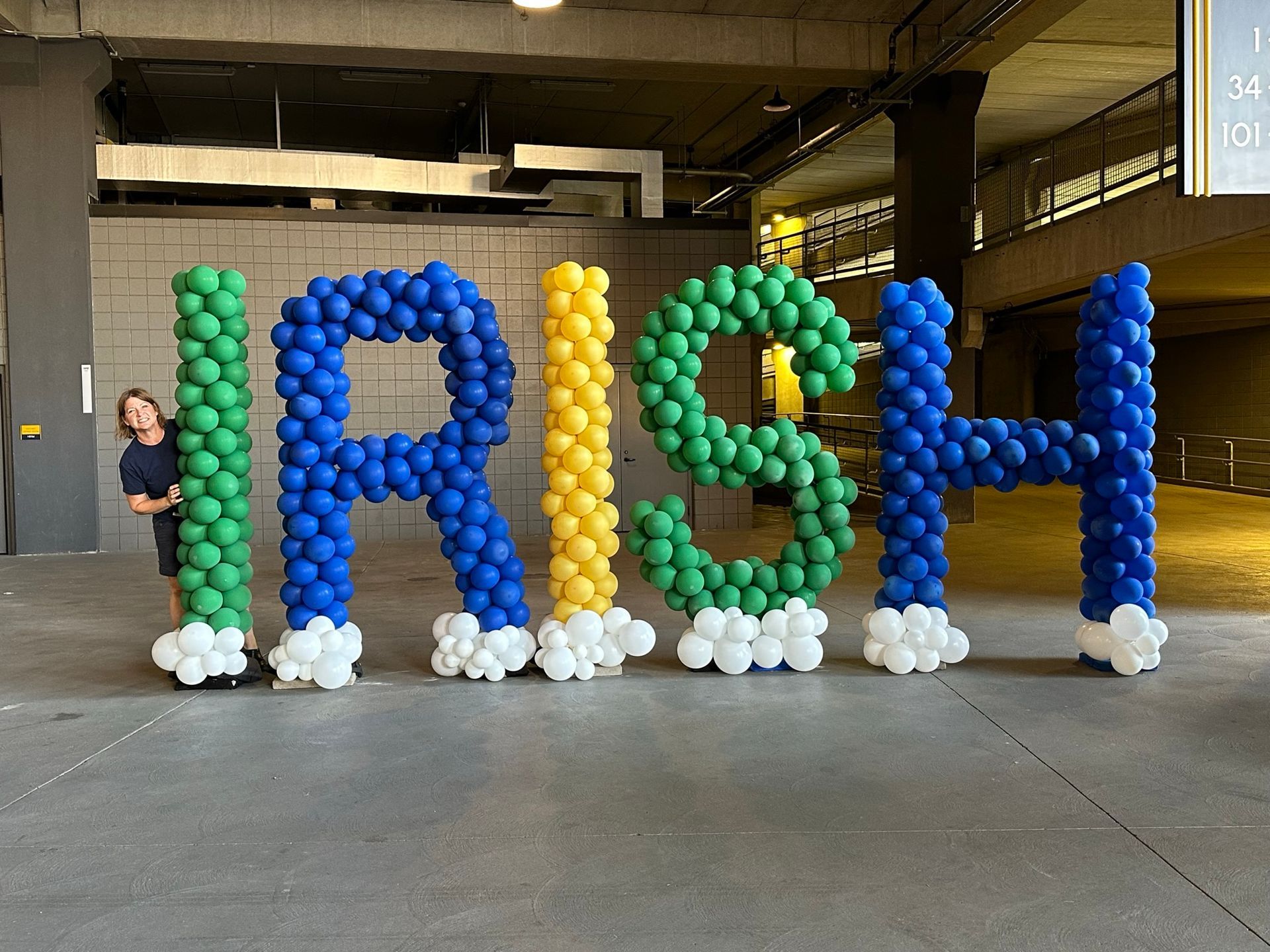 a woman is standing next to a sign made of balloons that says irish