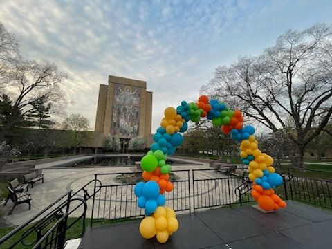 A colorful balloon arch is sitting on a stage in front of a building.