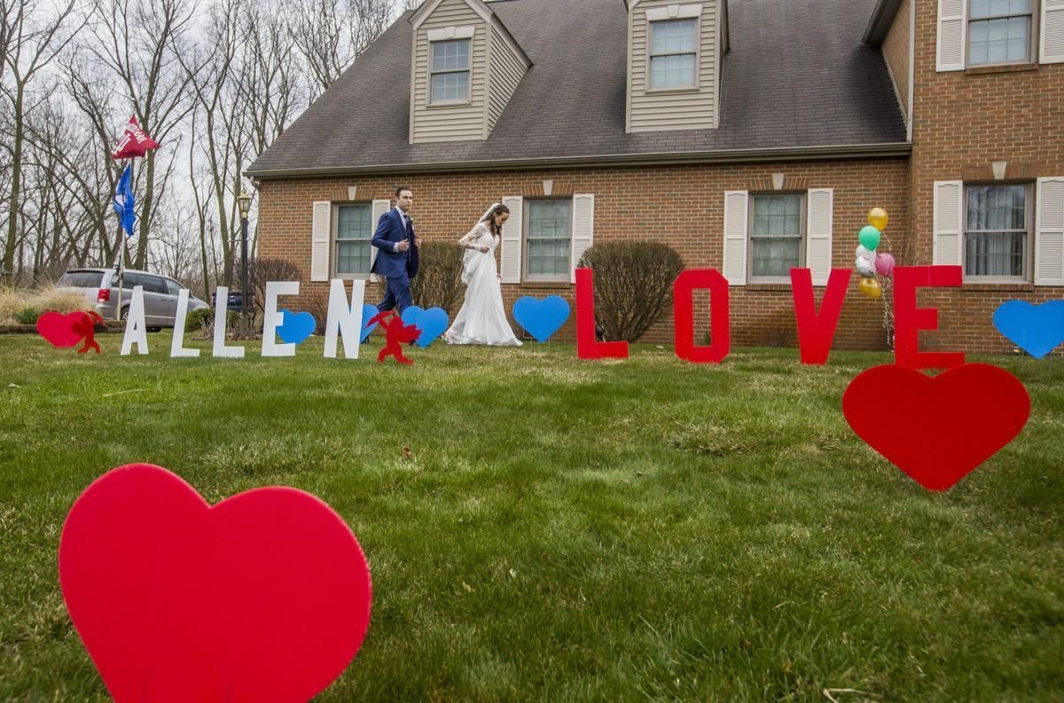 A bride and groom are posing for a picture in front of a house.