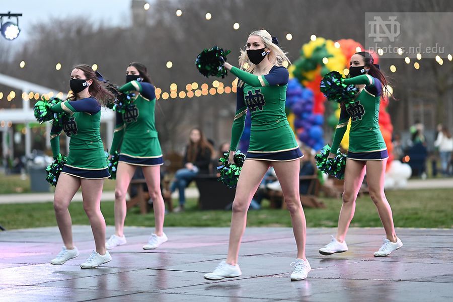 A group of cheerleaders wearing masks are dancing on a stage.