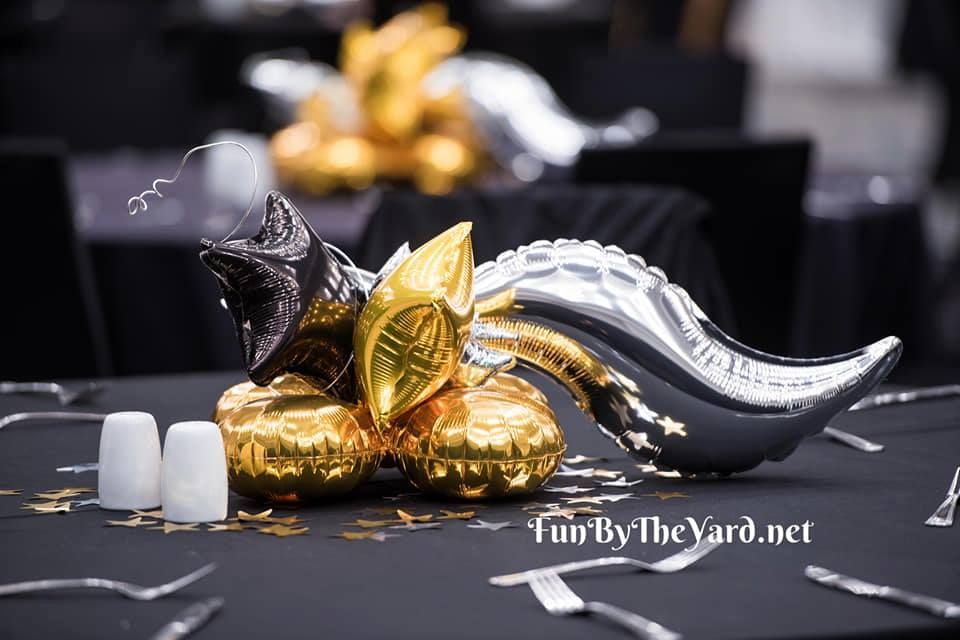 A bunch of gold and silver balloons on a table