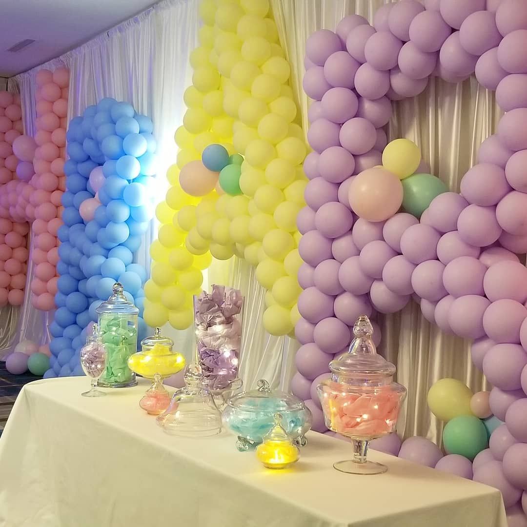 A table with jars of candy and balloons behind it. The world baby is spelled in balloons.