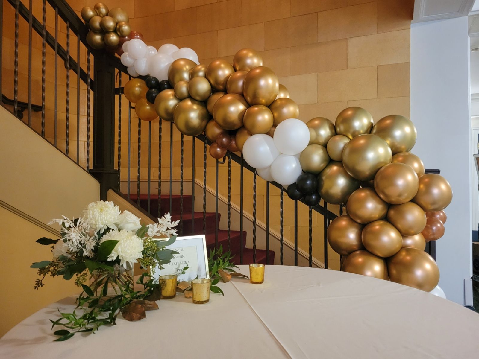 Gold, white, black balloon garland on stairway