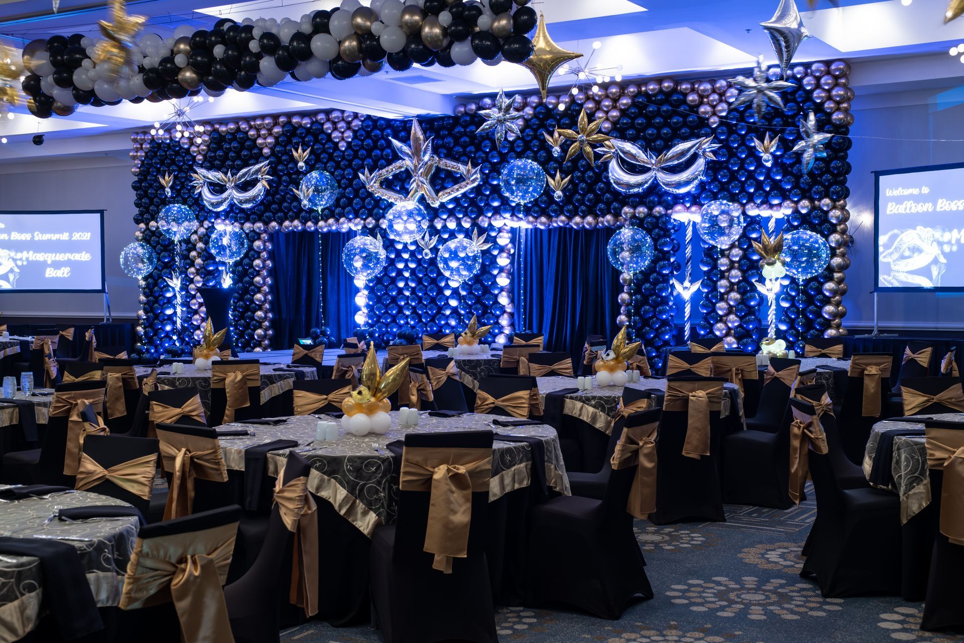 A large room with tables and chairs and balloons on the wall.