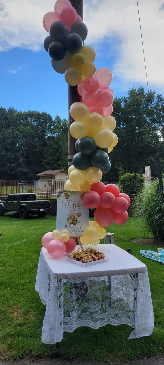 Table set with cake and snacks, decorated with colorful balloons on a sunny day.