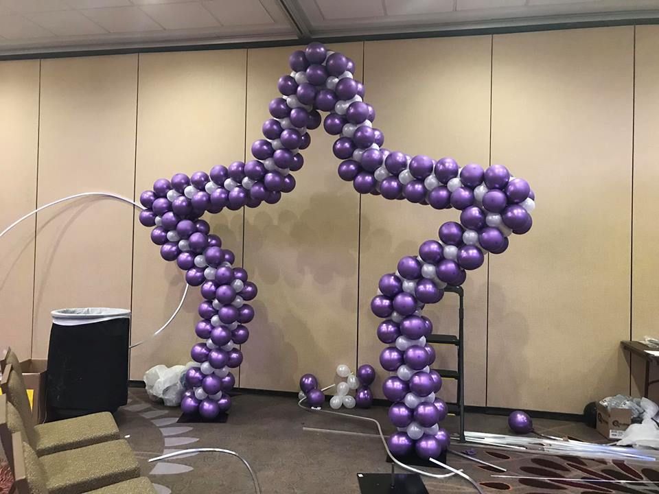 A star made of purple and silver balloons in a room. Balloon photo op.
