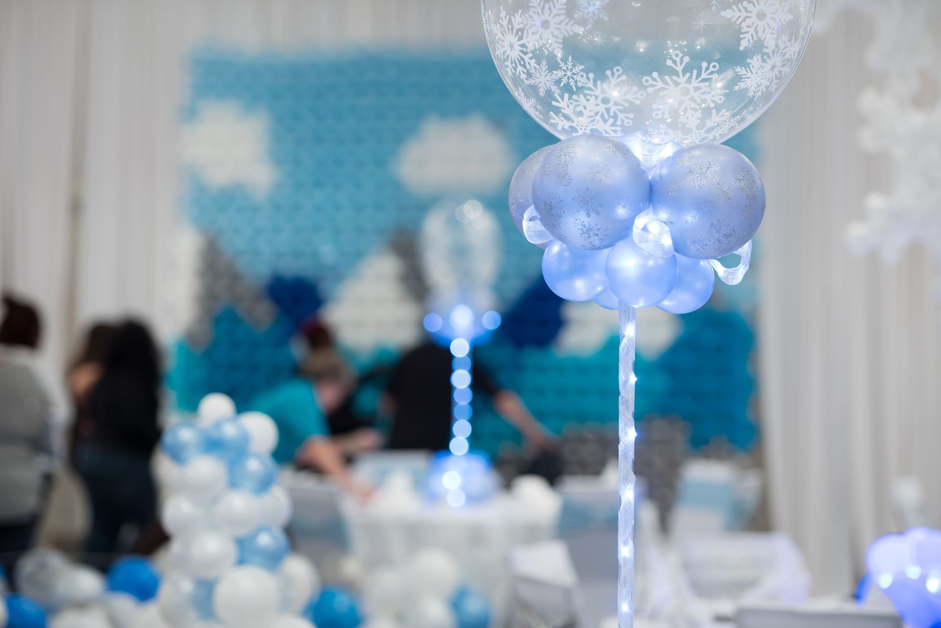 A room decorated with blue and white balloons and a balloon with snowflakes on it.