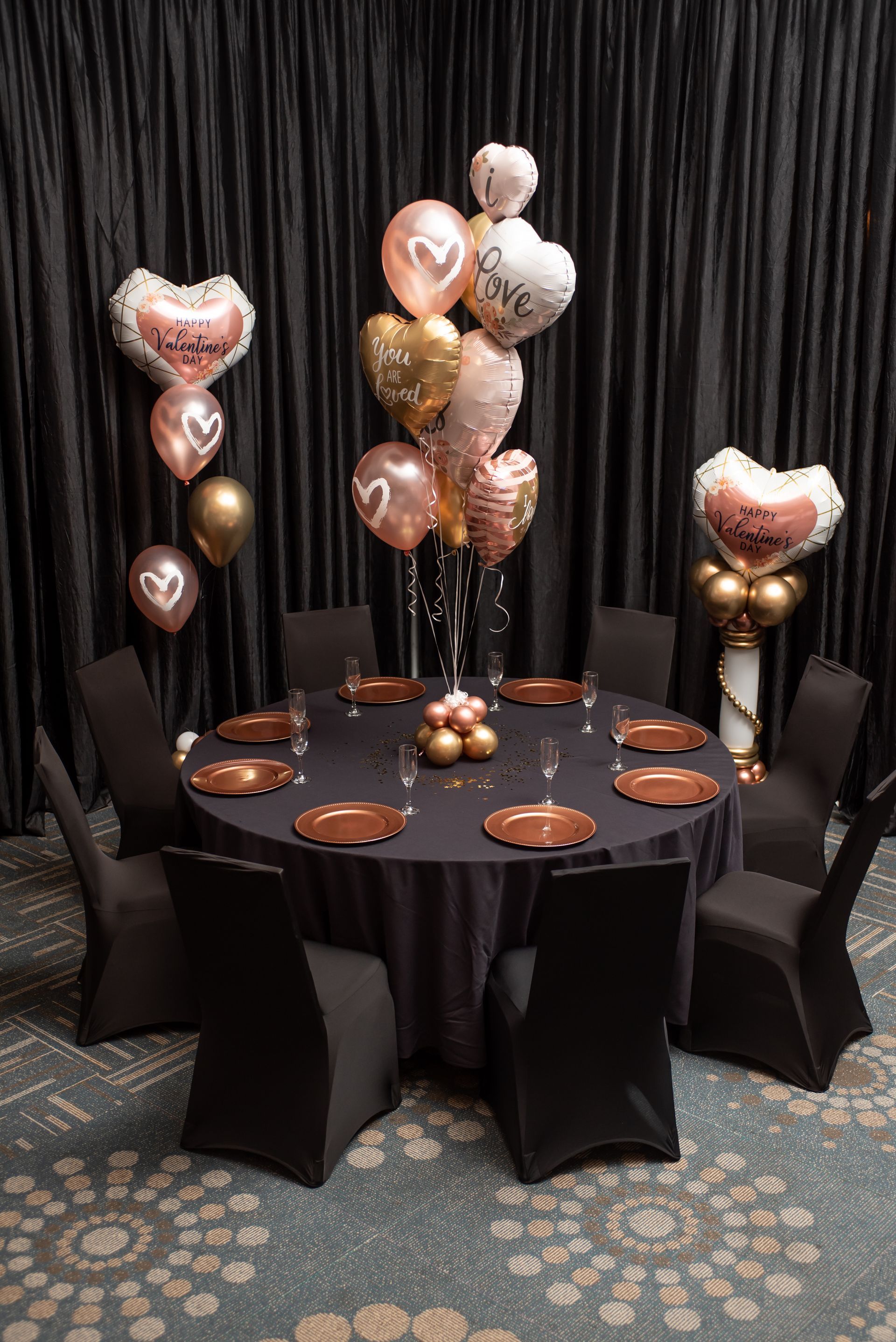 A table with plates and chairs and balloons on it for Valentin's day.