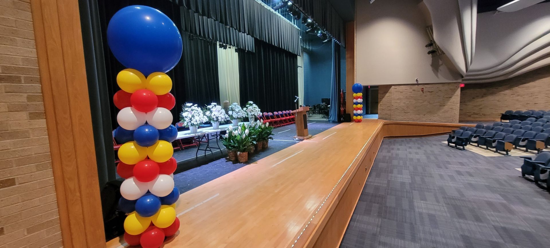 A large auditorium with a podium and balloons on the stage.