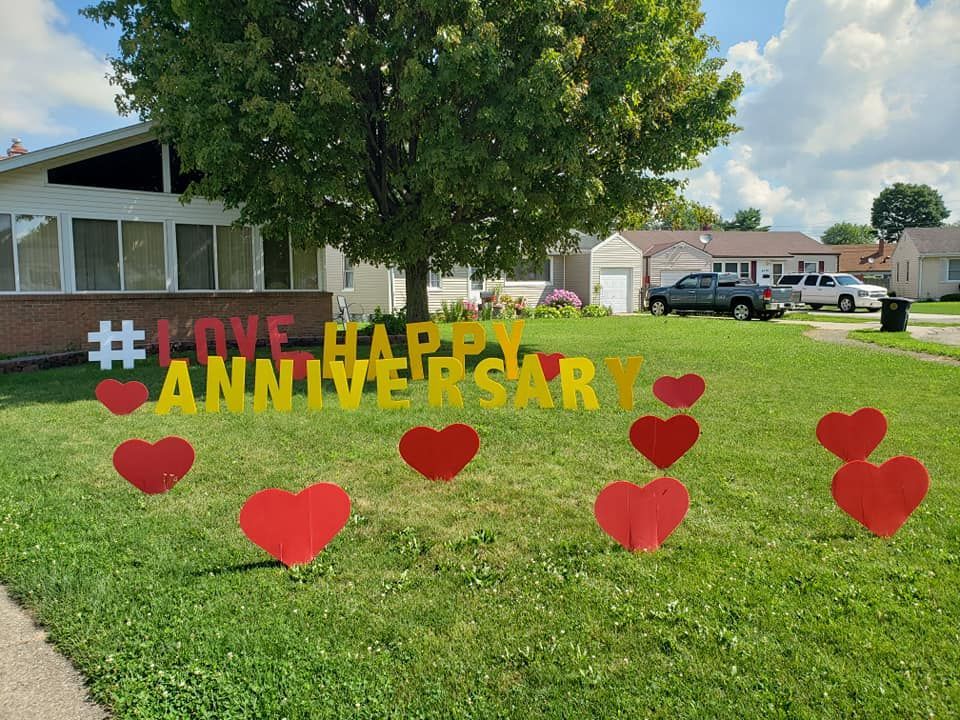A yard with a sign that says happy anniversary. Heart themed yard card.