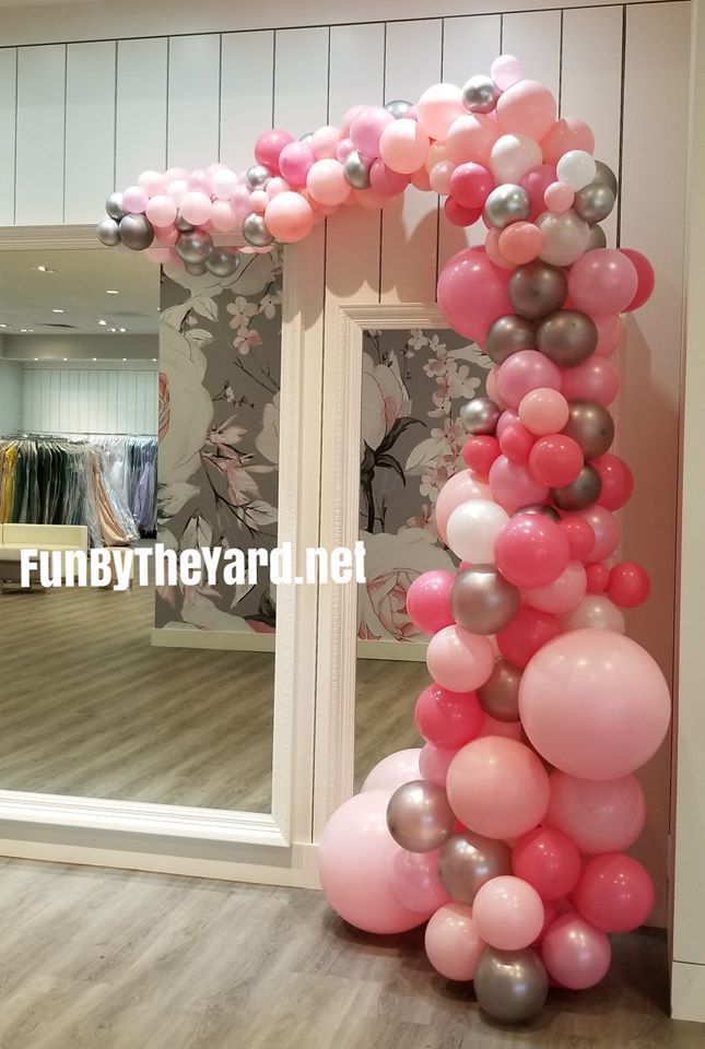 A bunch of pink balloons are sitting in front of a mirror in a room.