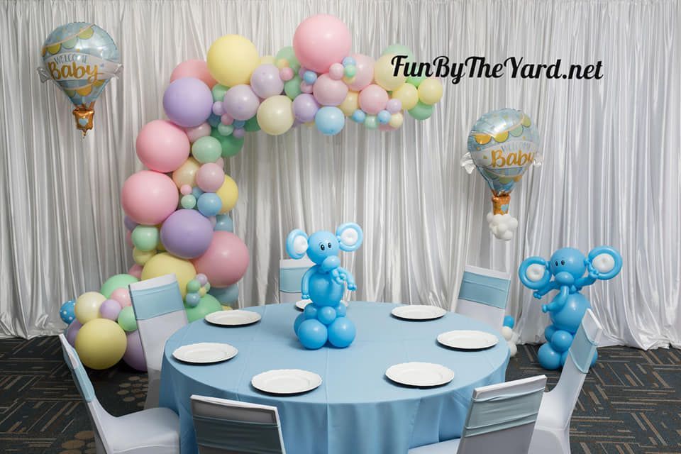 A table and chairs are decorated with balloons for a baby shower.