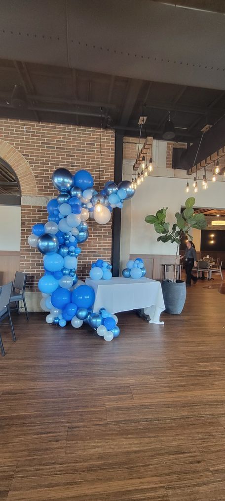 A room decorated for an event with a large blue balloon display and a table.