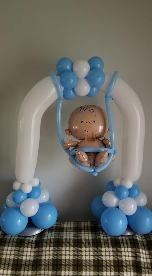 A baby is sitting on a swing made of balloons.