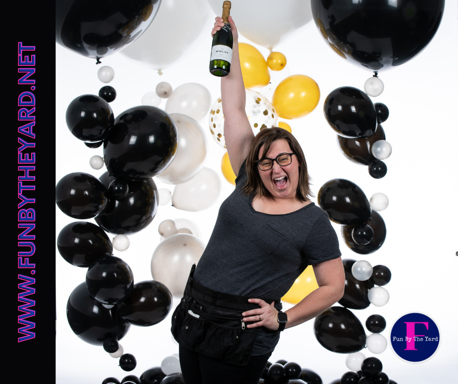 A woman is holding a bottle of champagne in front of balloons