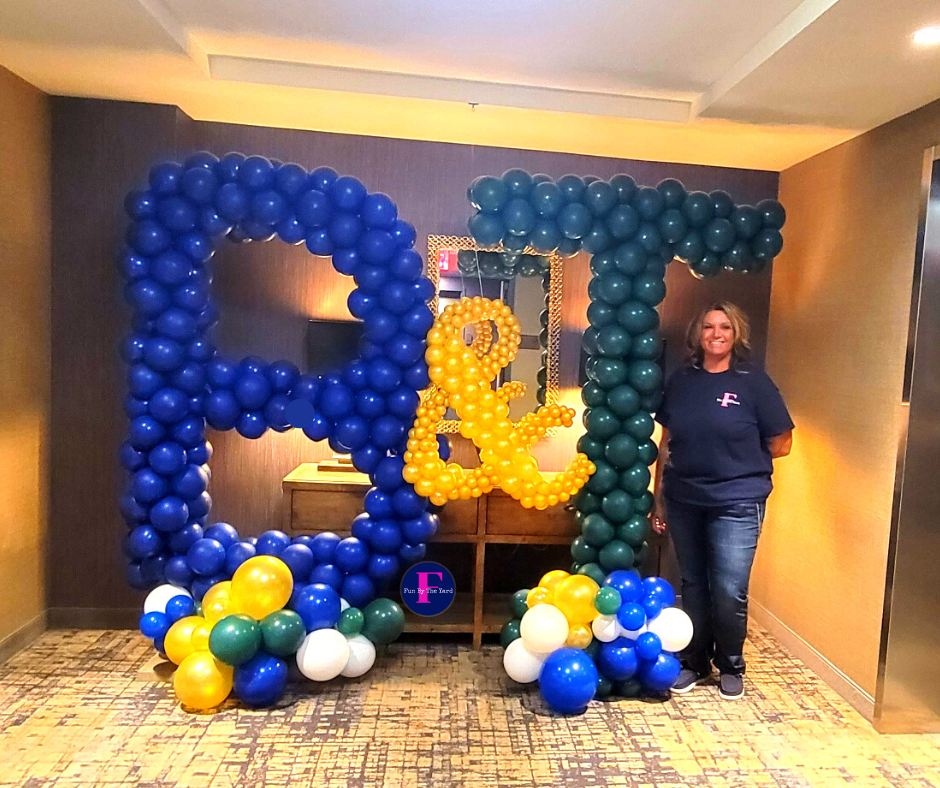 A woman is standing in front of a sign made of balloons. Barnes and Thronburg
