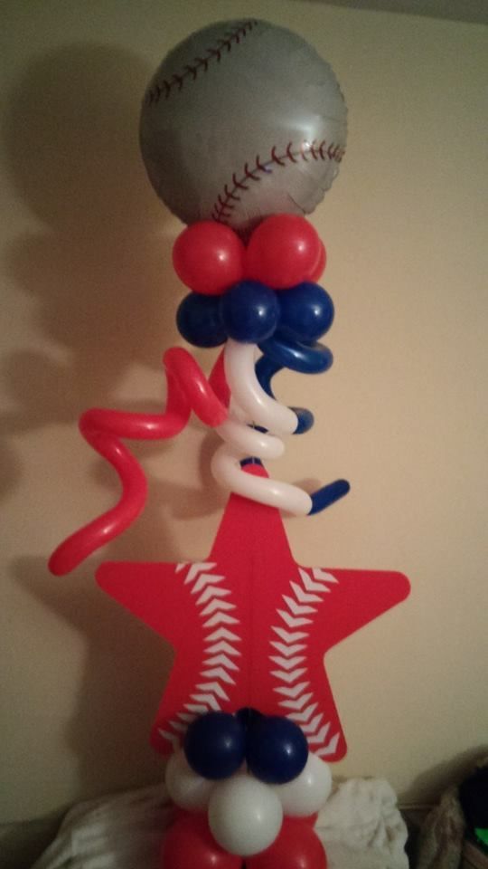 A baseball is sitting on top of a red star made of balloons.