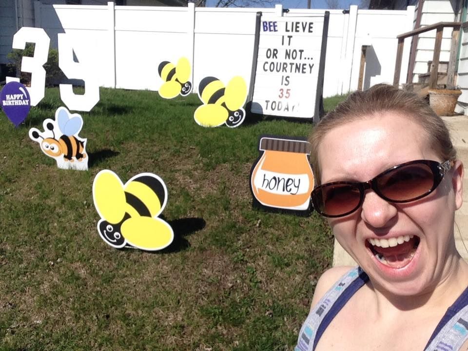 A woman in front of a sign that says bee lieve it