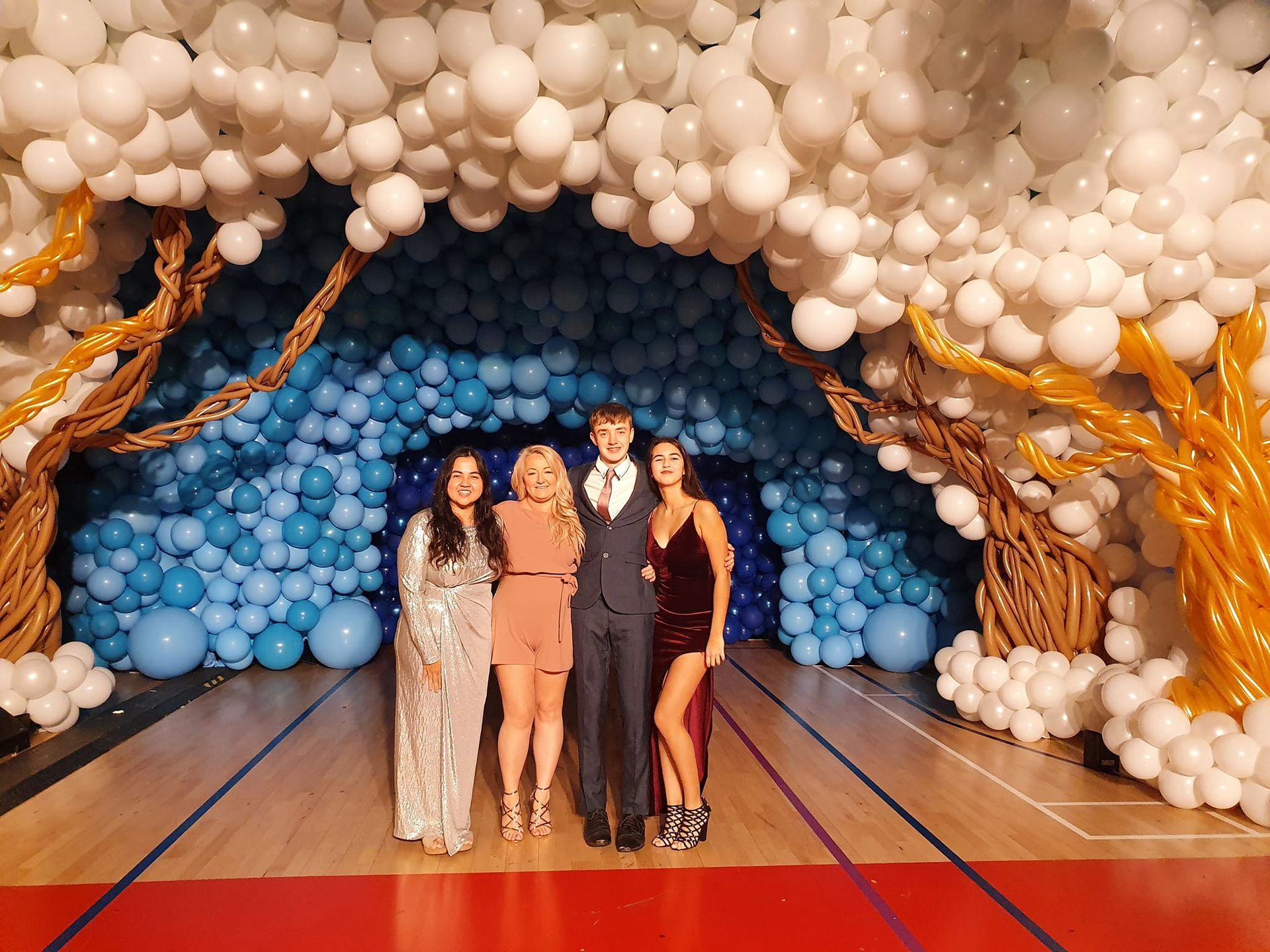 A group of people standing in front of a tunnel of balloons.