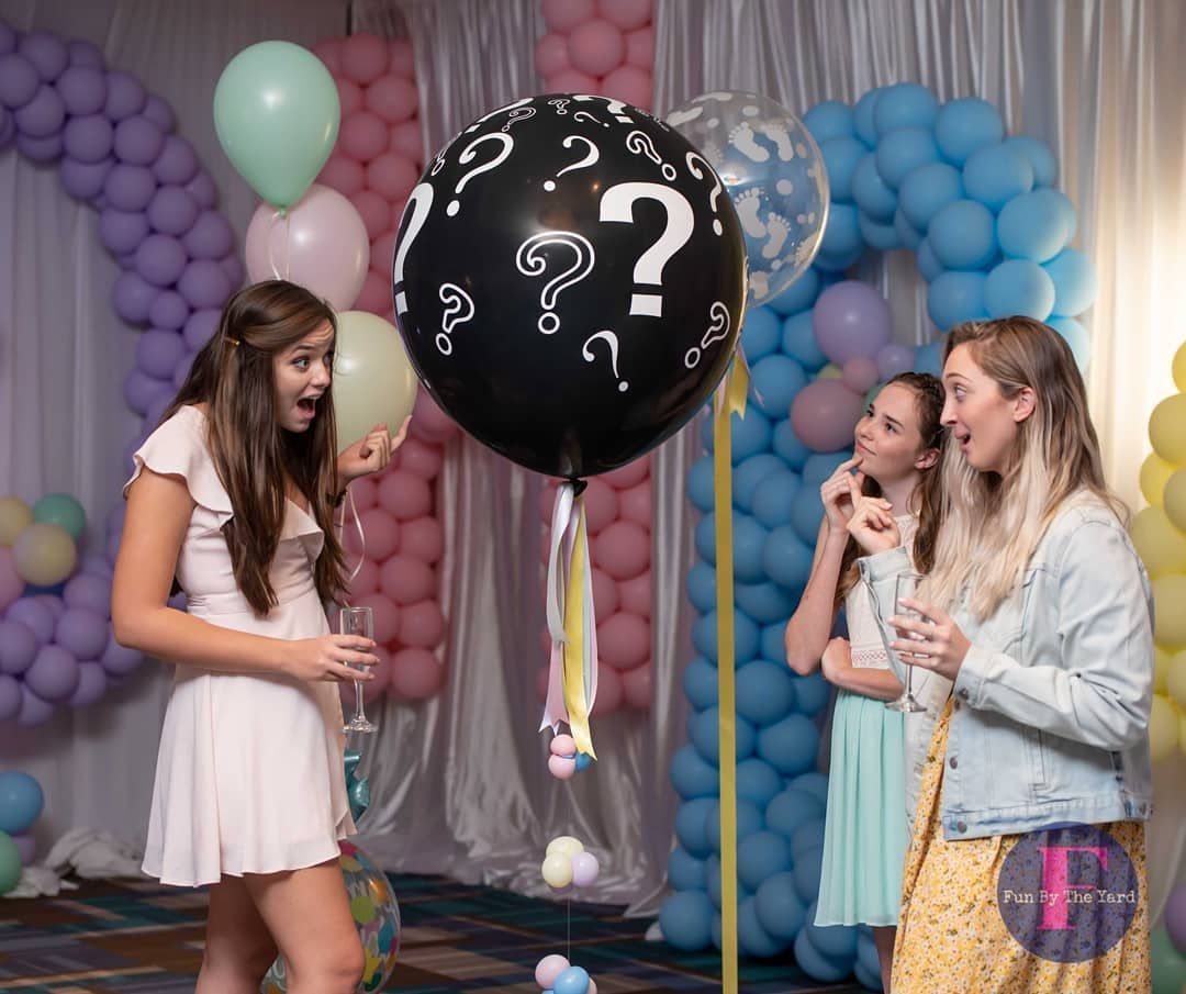 A woman is holding a balloon with a question mark on it.