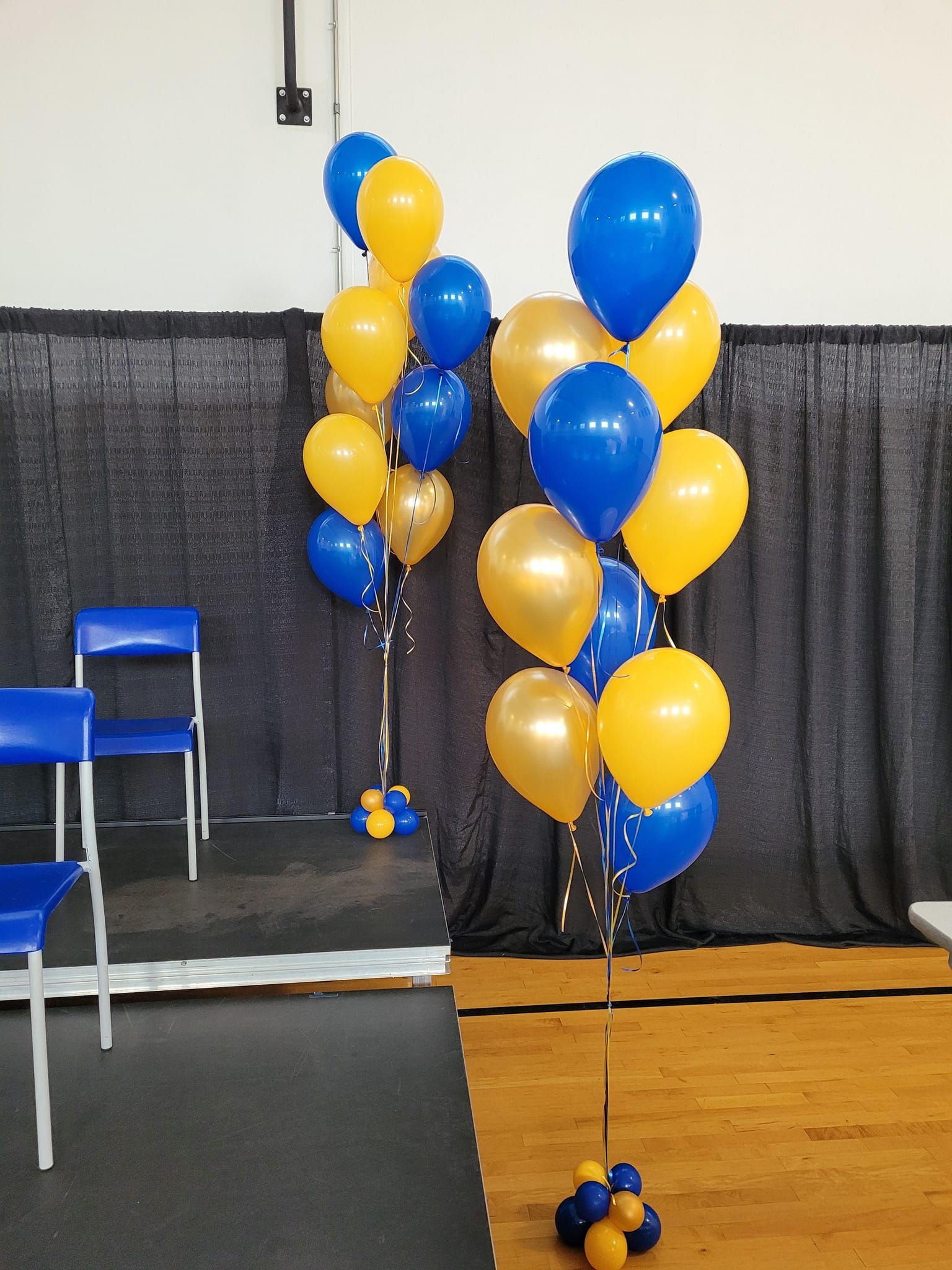 Helium balloon bouquets in blue and yellow on a stage
