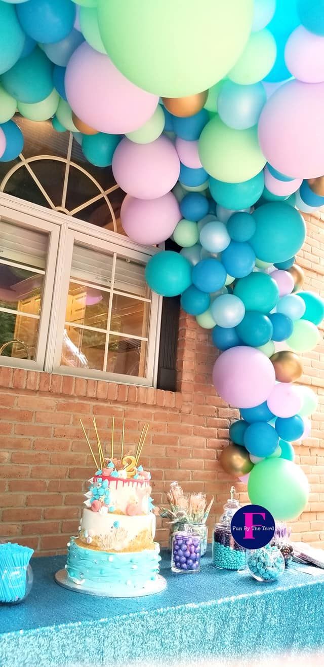 A table with a cake and balloons hanging from the ceiling.