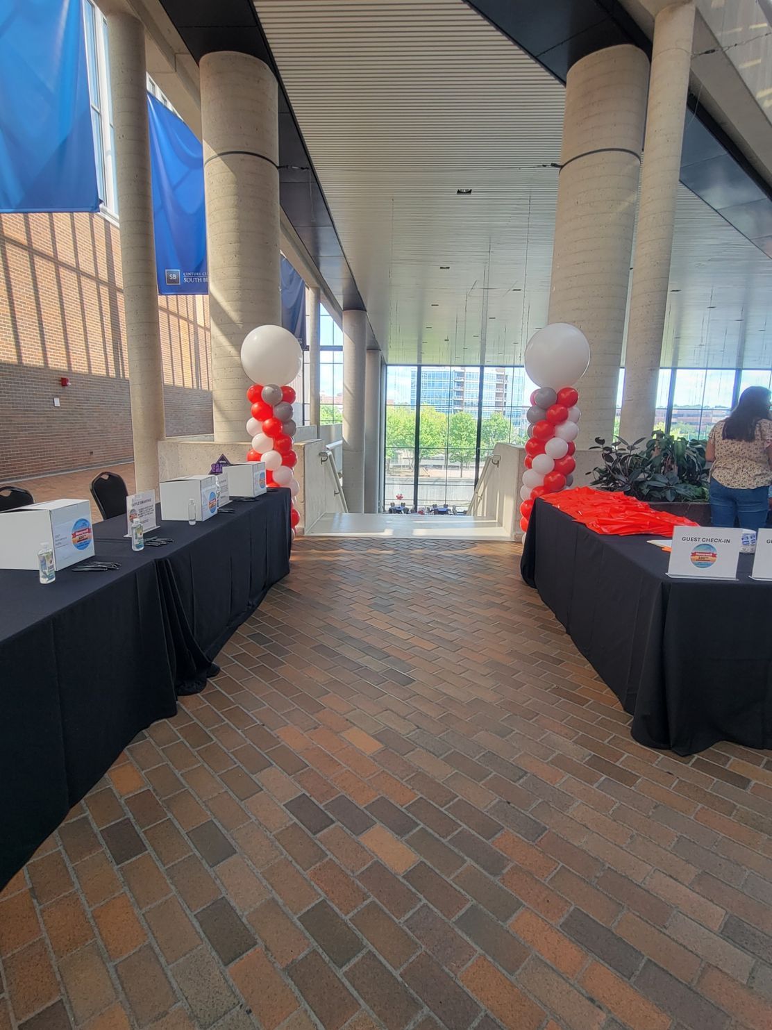 A hallway filled with tables and balloons in a building.