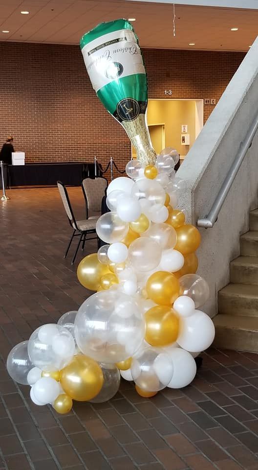A bottle of champagne is floating in the air surrounded by balloons.