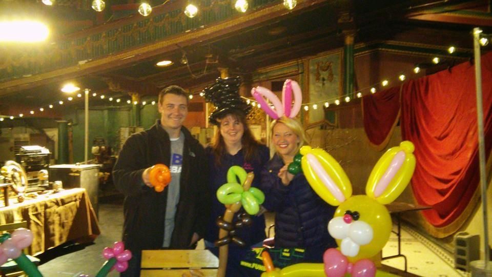 A group of people are standing next to each other with balloons in the shape of animals.