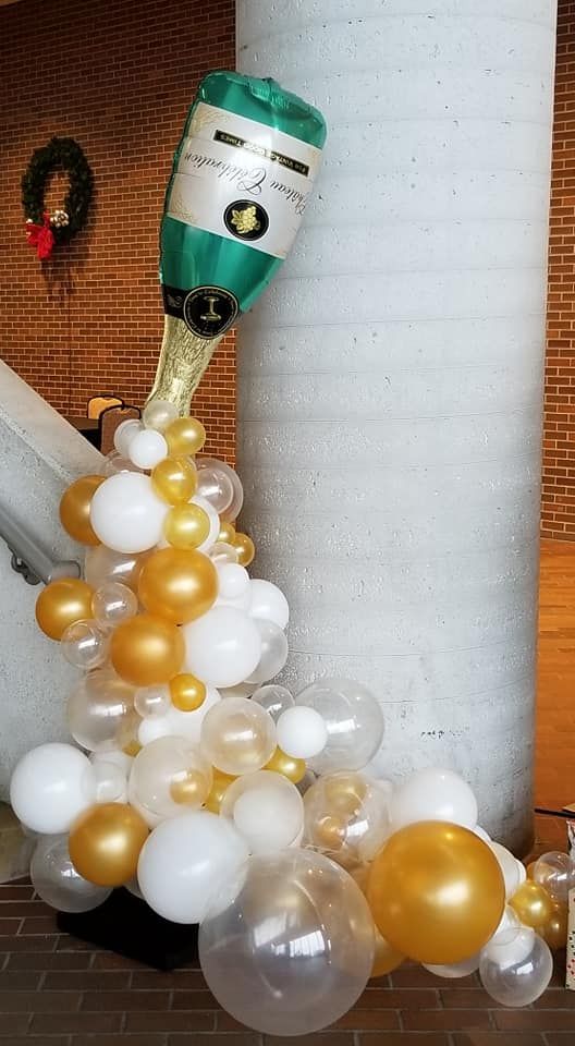 A bottle of champagne is being poured out of a balloon.