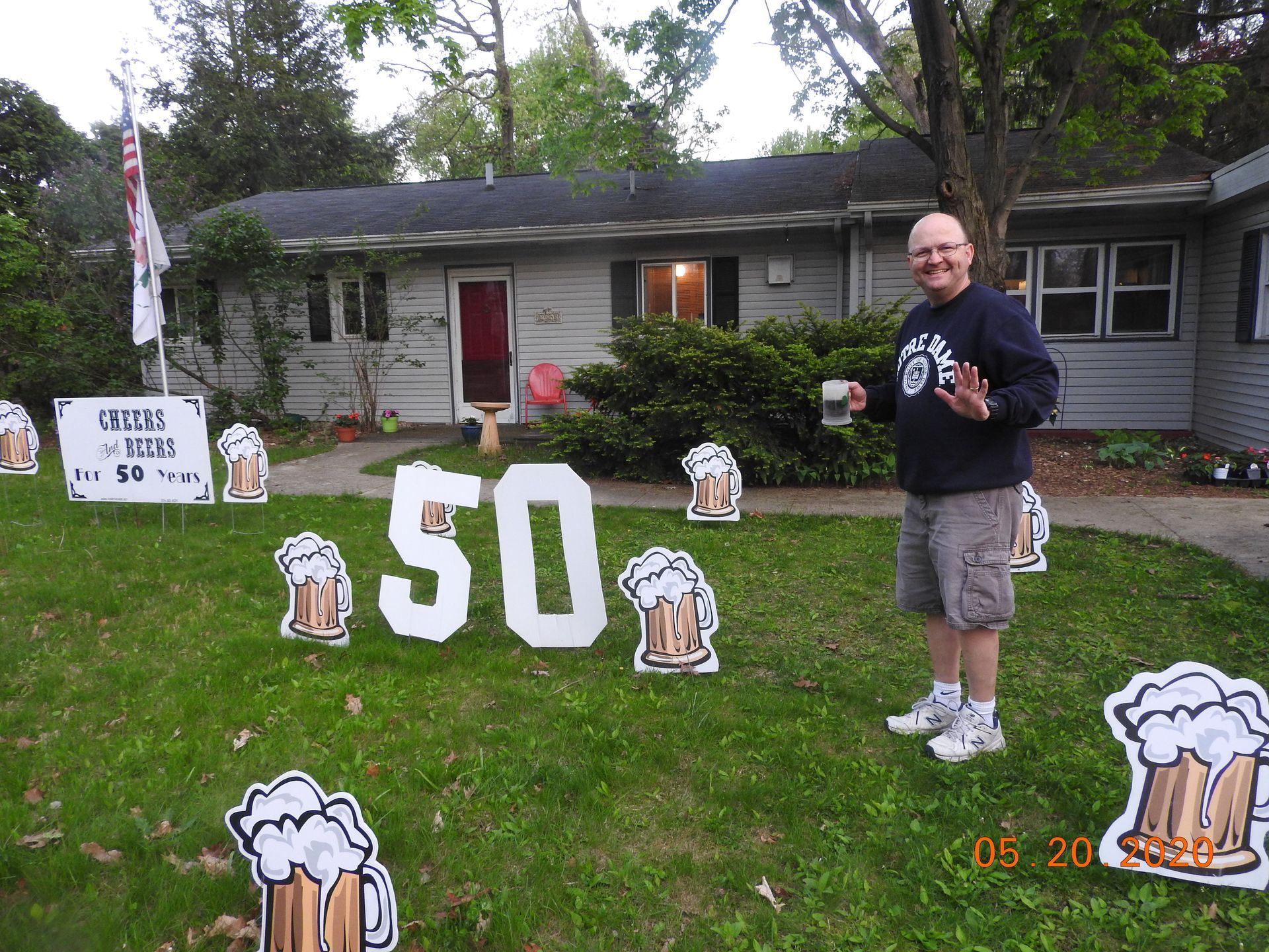 A man stands in front of a sign that says 50.  Beer themed yard card.