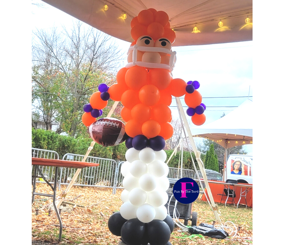 Balloon sculpture of a football player in orange, purple, white, and black, holding a football.