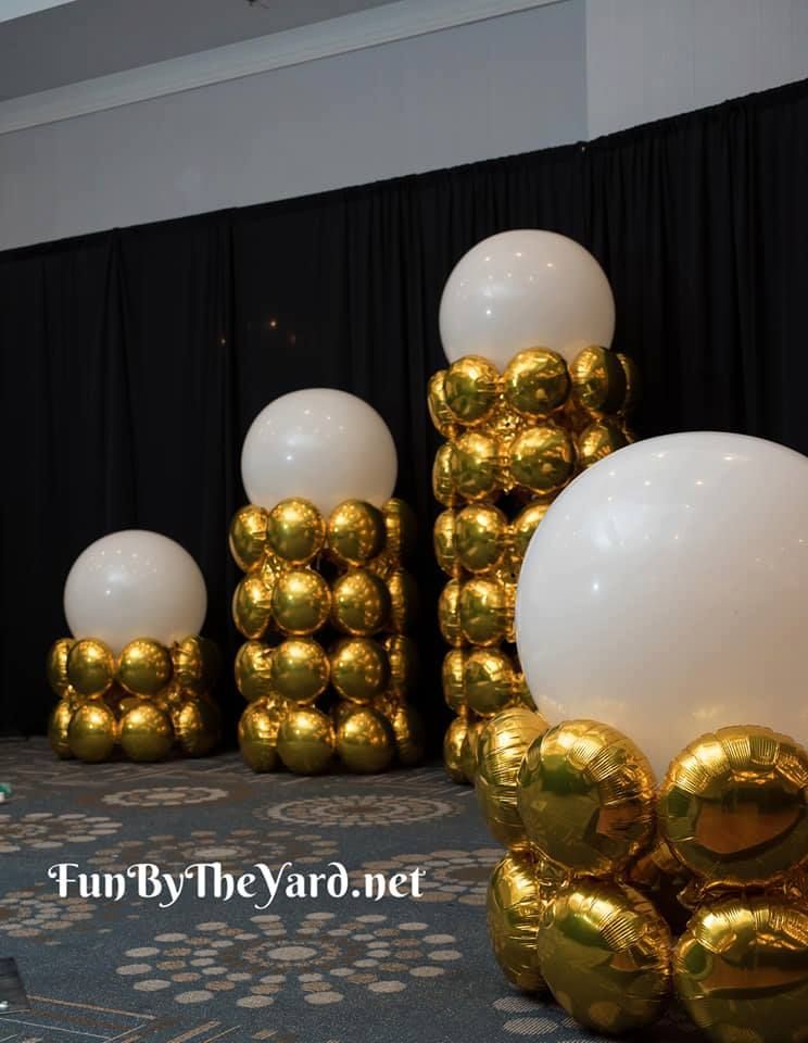 A bunch of gold and white balloons stacked on top of each other