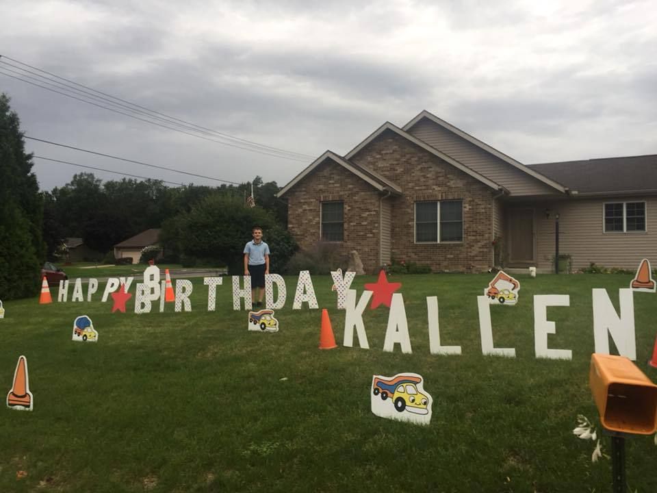 A man is standing in front of a yard sign that says happy birthday kaleen