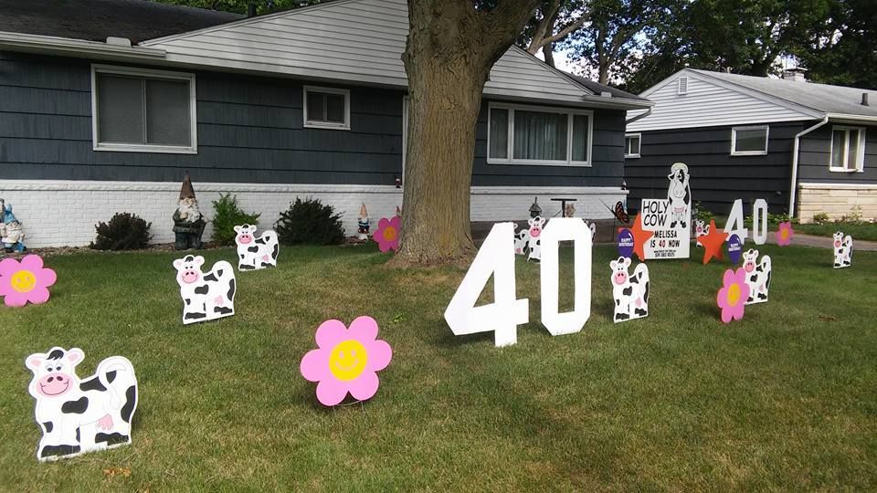 A yard decorated for a 40th birthday with cows and flowers