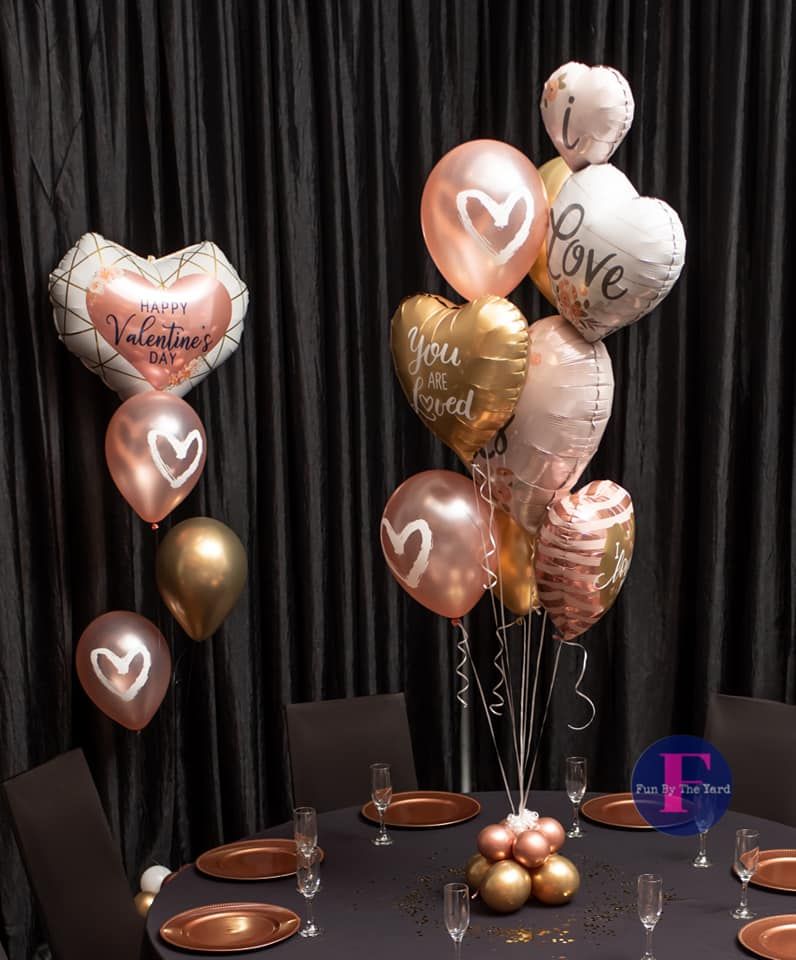 Valentines Day balloon bouquets are sitting on top of a table.