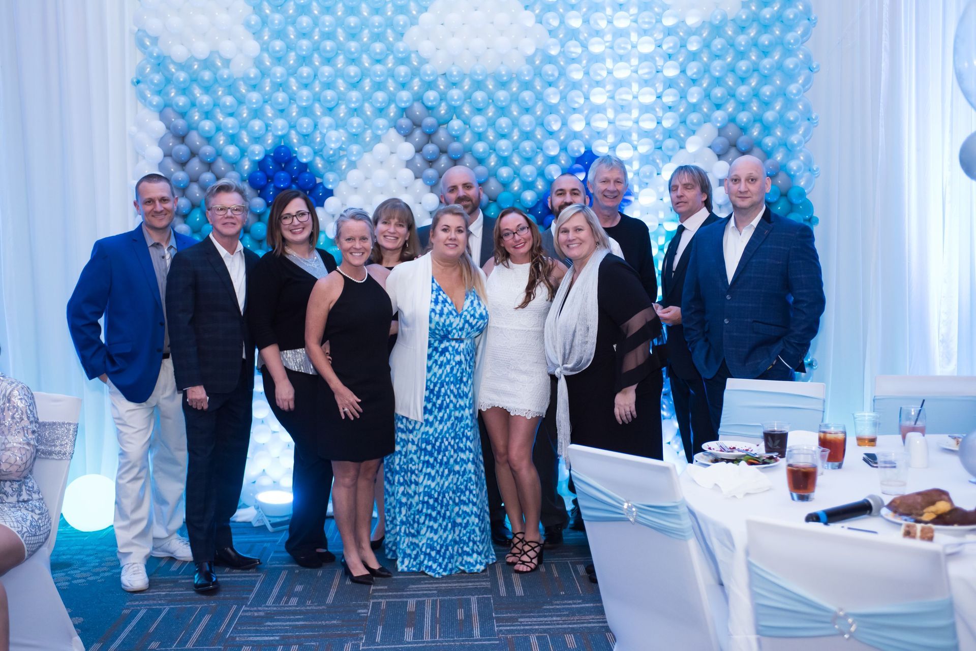 A group of people are posing for a picture in front of a wall of balloons.
