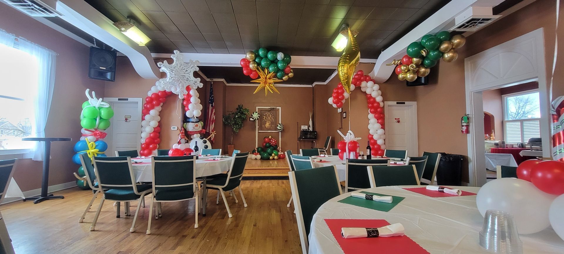 A large room with tables and chairs decorated for a christmas party.