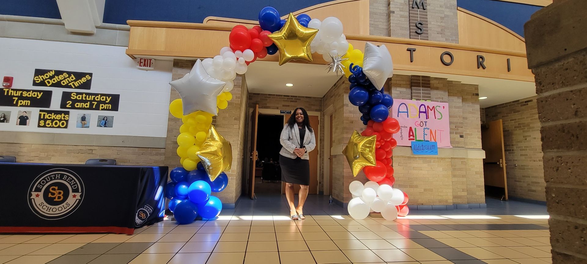 A woman is standing in front of a building decorated with balloons.